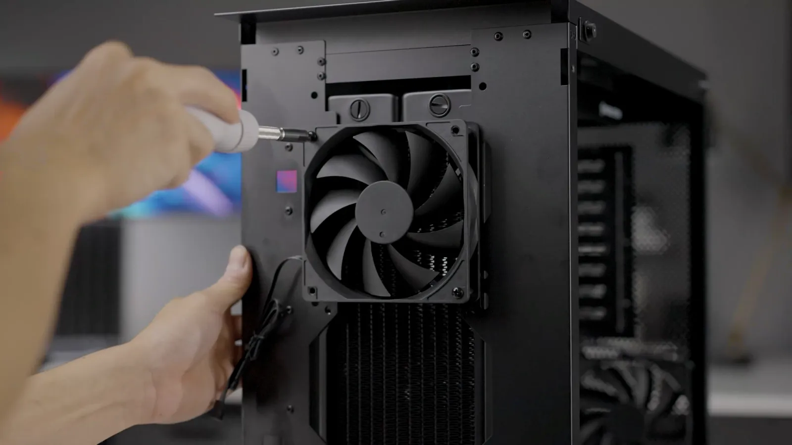 Hands fitting a fan to a chassis