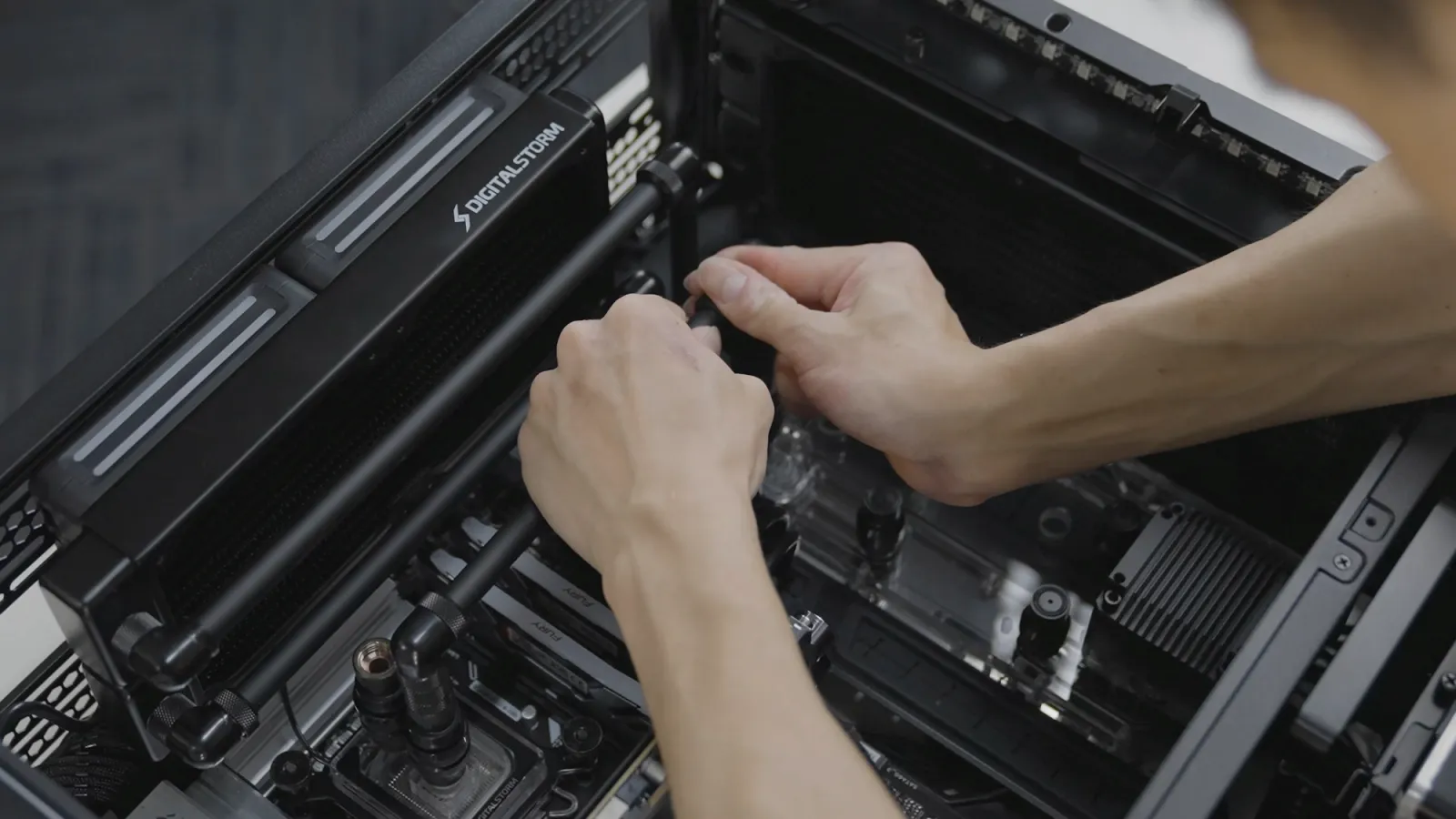 Hands fitting liquid-cooling tubing inside a chassis